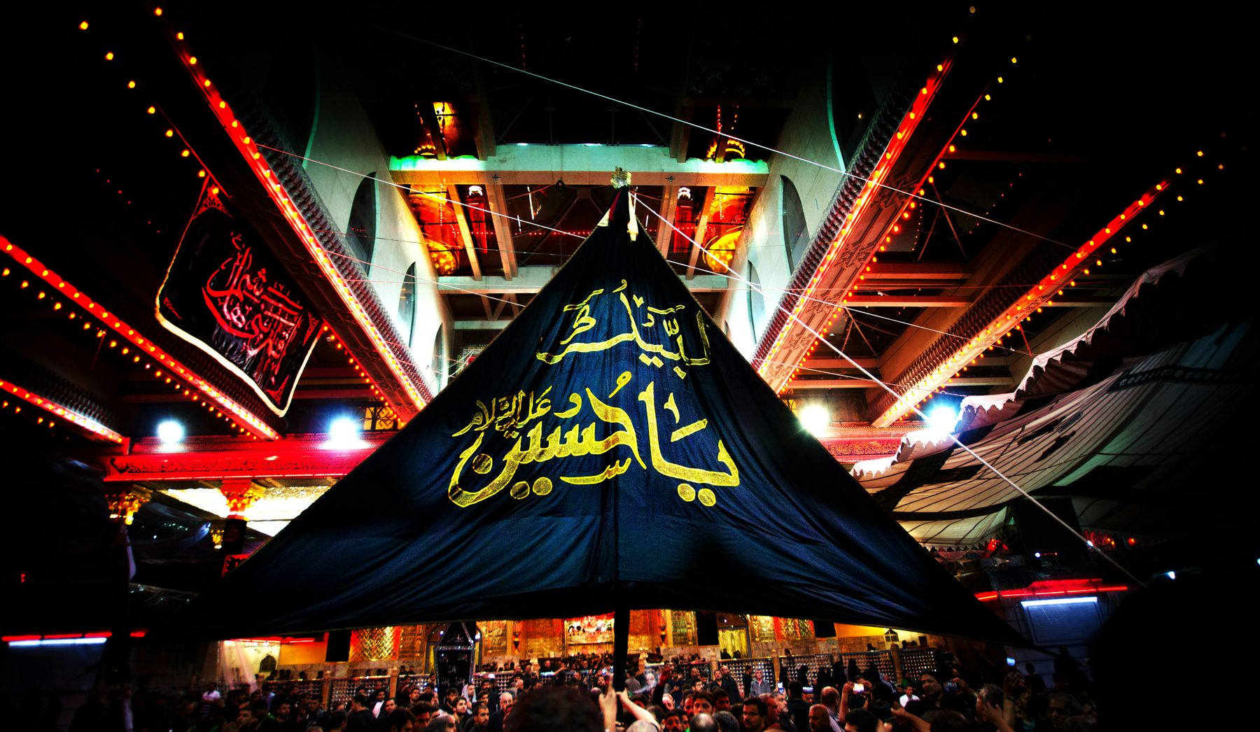 Illuminated shrine and black alam at night
